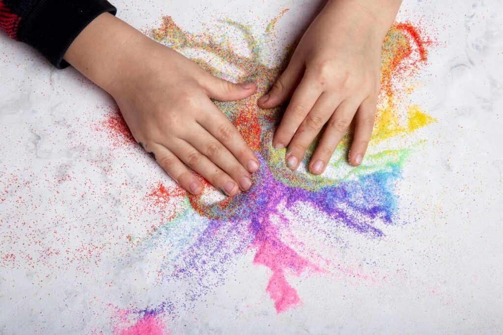 child hands playing with rainbow colored sand mot 2026 01 08 06 35 32 utc